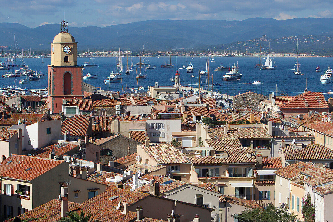 France, Var department, a large view on the old roofs and the church of the city of Saint-Tropez with in background yachting boats