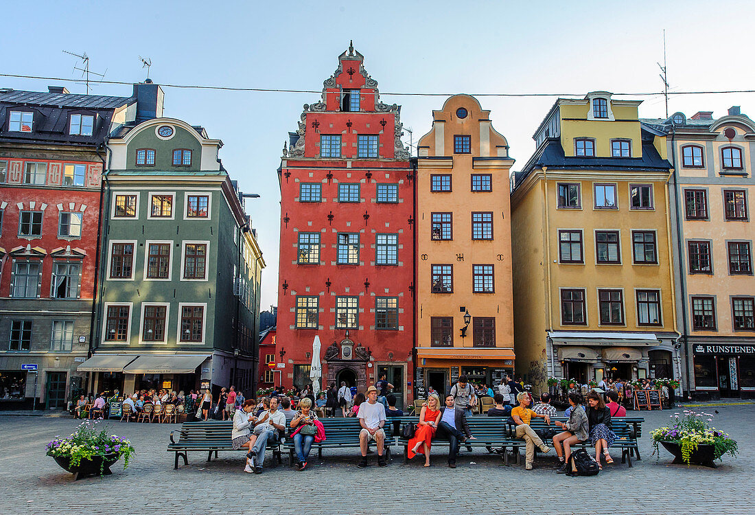 People sit on park benches in the main square Stortorget in the old town Gamla Stan, Stockholm, Sweden