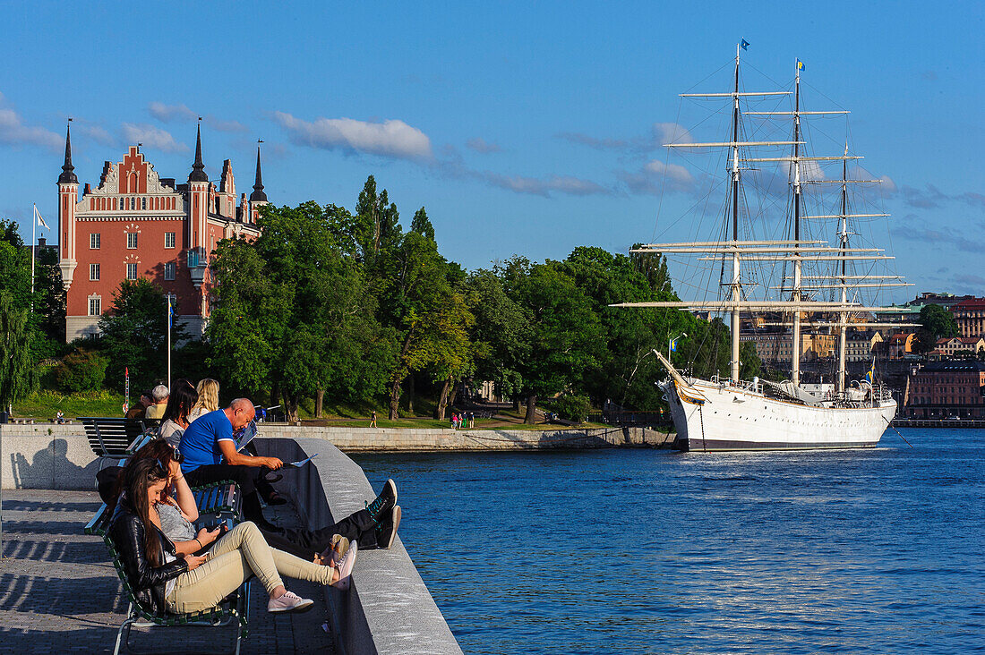 Hostel on the sailing ship Vandrarhem af Chapman and Skeppsholmen. People in front of park bench, Stockholm, Sweden