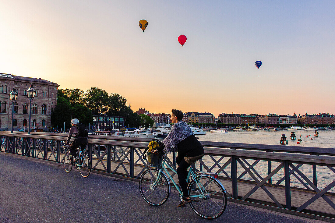 Cyclist on the Skeppsholmsbron. Hot air balloons in the background, Stockholm, Sweden