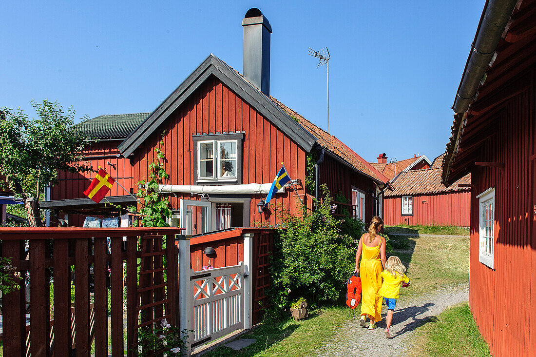 Frau mit Kind zwischen Schwedenhäusern auf der  beliebten Ausflugsinsel Sandhamn , Stockholm, Schweden