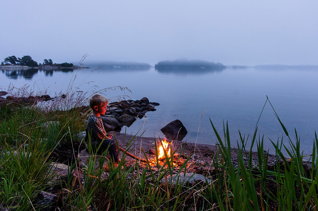 little boy at the campfire in the archipelago island Fiskhamn, Stockholm, Sweden