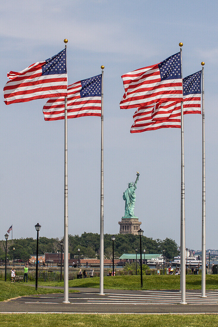 perspective of the statue of liberty with american flags in the foreground, new york harbor, new york city, state of new york, united states, usa
