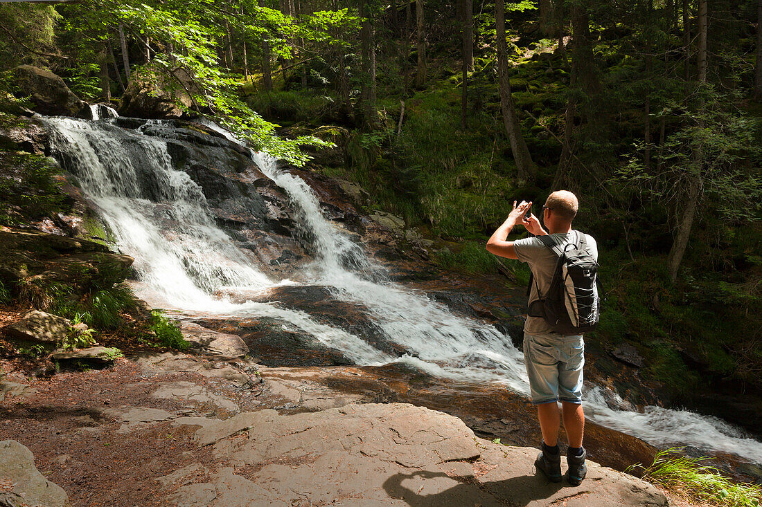 Mann fotografiert die Rissloch-Wasserfälle bei Bodenmais, Bayrischer Wald, Bayern, Deutschland