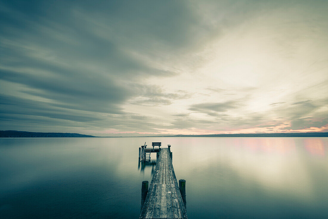 jetty with a bench and dramatic sky, lake Ammersee, Bavaria, Germany