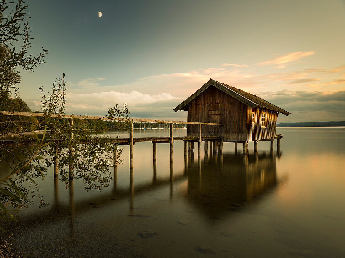 Moon above a boathouse near Stegen at lake Ammersee, Bavaria, Germany