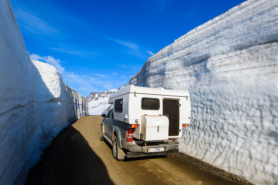 Offroad-Camper am Pass zwischen meterhohen Schneewänden, Ostfjorde, Island