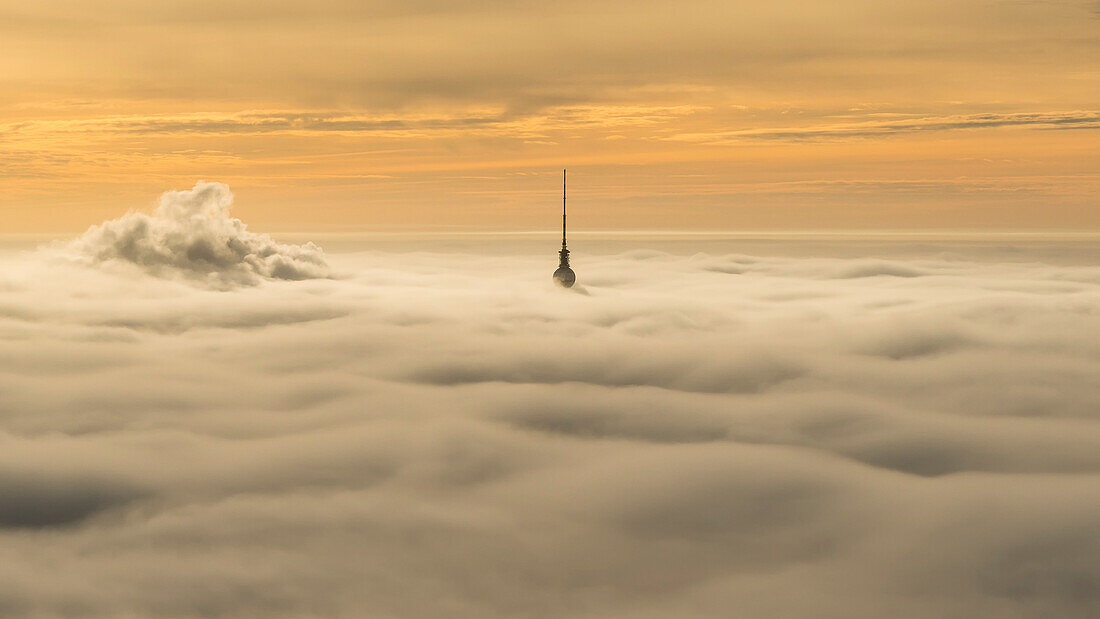 just the top of the TV-tower sticks out of the dense fog above Berlin, Germany