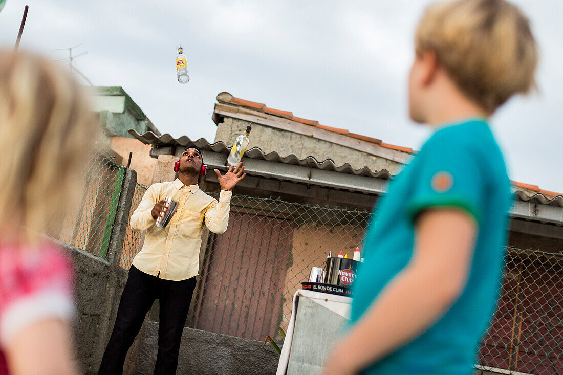 barman juggling with rum bottles on the beach of Playa Larga, family travel to Cuba, parental leave, holiday, time-out, adventure, Playa Larga, bay of pigs, Cuba, Caribbean island