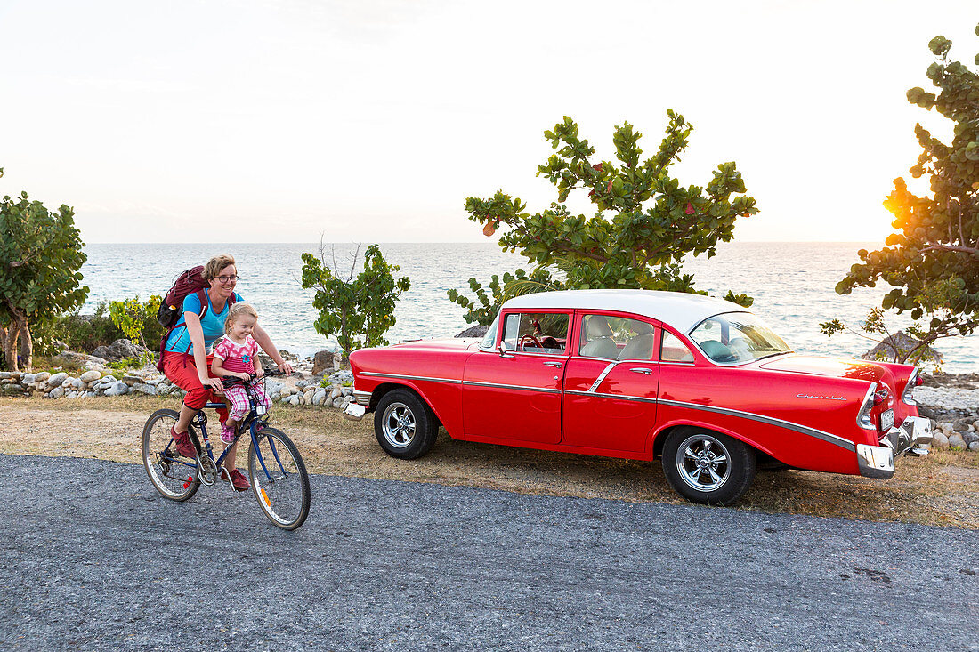 red oldtimer, woman with kid cycling along the lonely coast road from La Boca to Playa Ancon, with beautiful small beaches in between, turquoise blue sea, family travel to Cuba, parental leave, holiday, time-out, adventure, MR, La Boca, Trinidad, Cuba, Ca