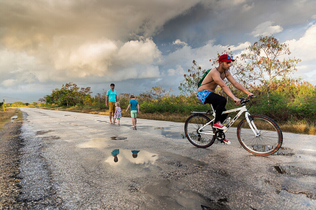 family jumping in puddles after the rain, lonely coast road from La Boca to Playa Ancon, with beautiful small beaches in between, turquoise blue sea, family travel to Cuba, parental leave, holiday, time-out, adventure, MR, near Trinidad, Cuba, Caribbean i
