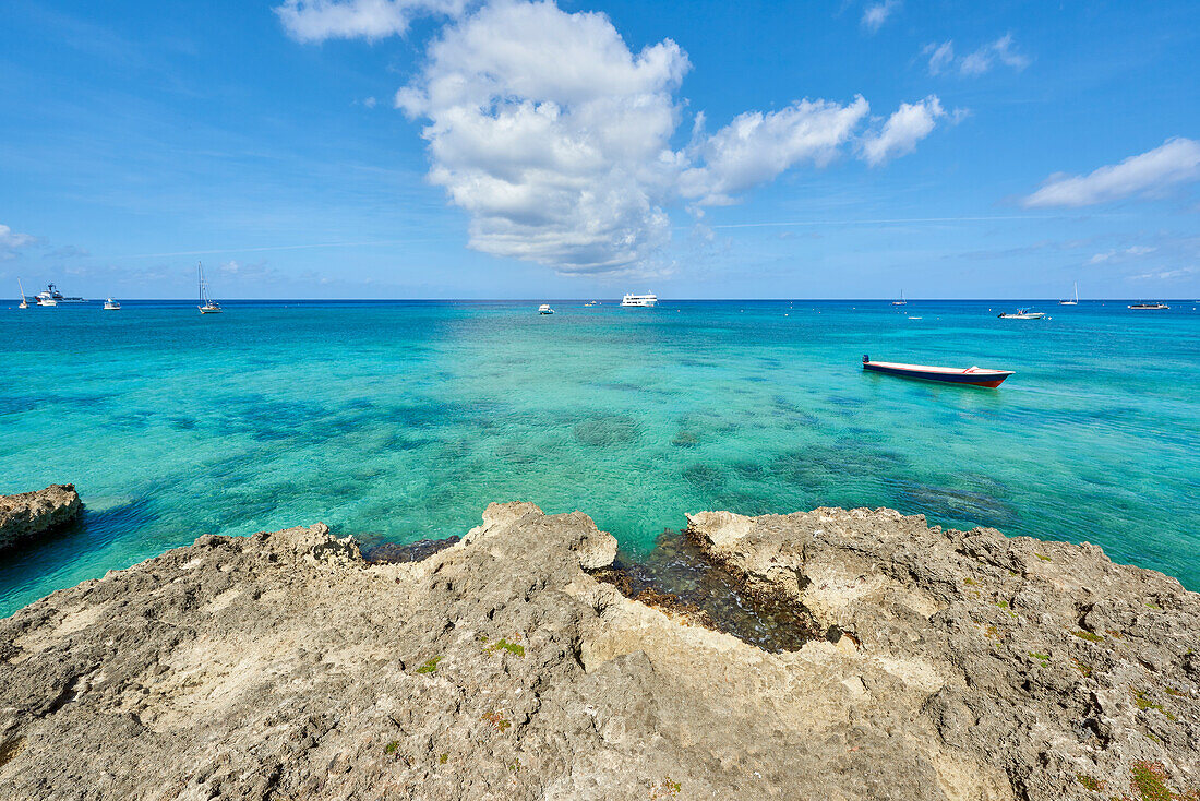 Rocky coastline in Cayman Islands with fishing boat in the transparent blue water, Cayman Islands, West Indies, Caribbean, Central America