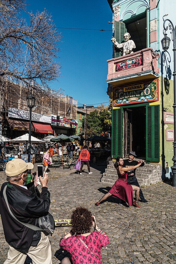 Street tango dancer hamming it up with tourists outside a bar on the corner of El Caminito, La Boca, Buenos Aires, Argentina, South America