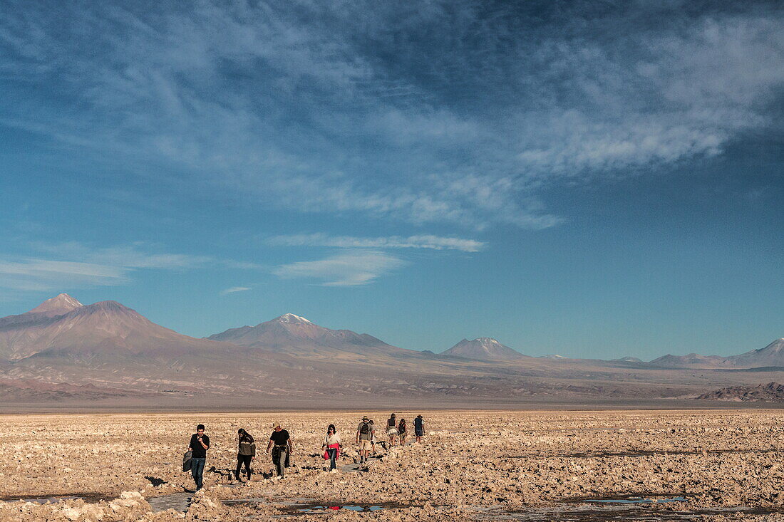 Hikers out on the Atacama Salt Flats, with snow-capped volcanic peaks in the background, near San Pedro de Atacama, Chile, South America