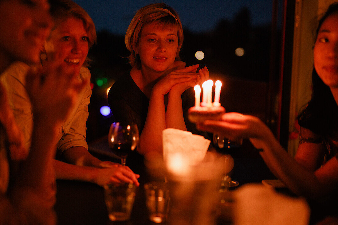 Female friends celebrating birthday at home during night