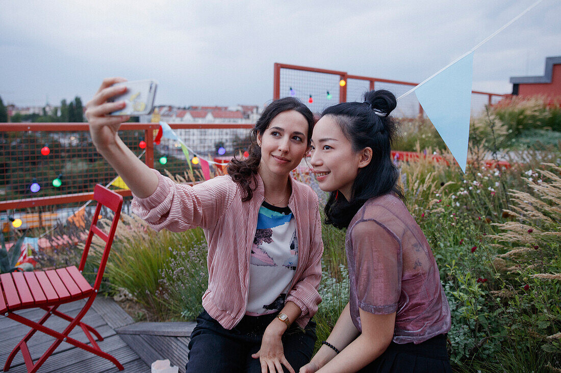 Smiling women taking selfie with smart phone on patio