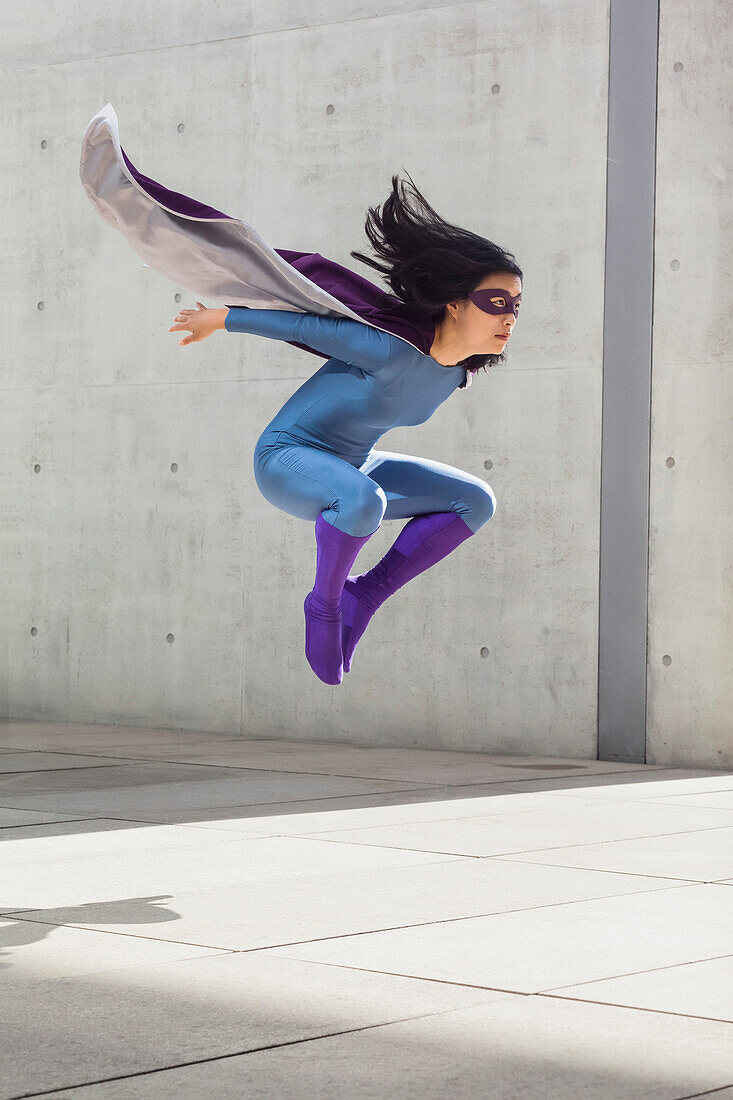 Weibliche Superheldin, die in der Luft gegen eine Wand levitiert