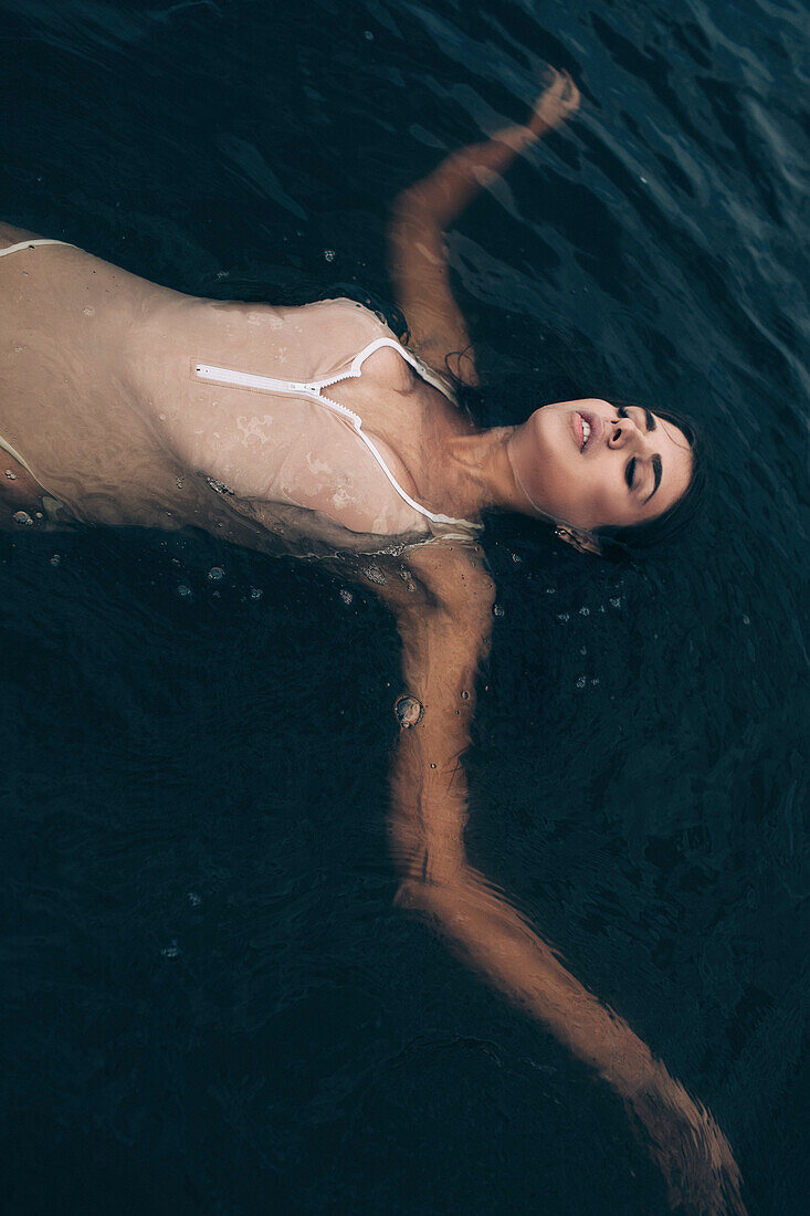 Hohe Winkel Ansicht der sinnlichen Frau mit ausgestreckten Armen Schwimmen im See