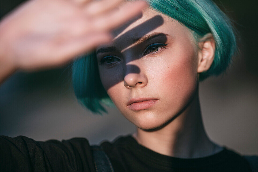 Close-up of teenage girl shielding eyes on sunny day