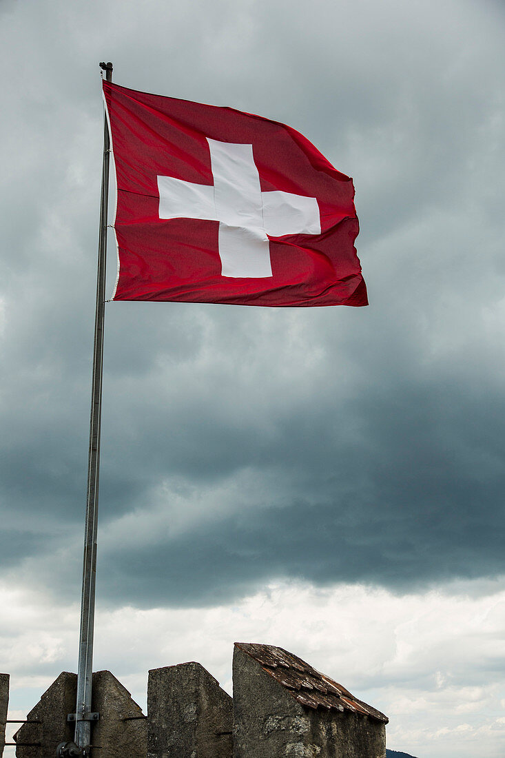 Low angle view of Swiss Flag flapping in wind against cloudy sky