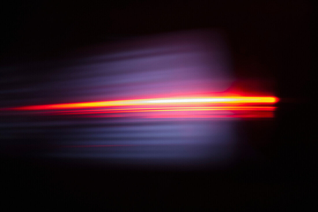 Close-up of abstract red light trail against black background