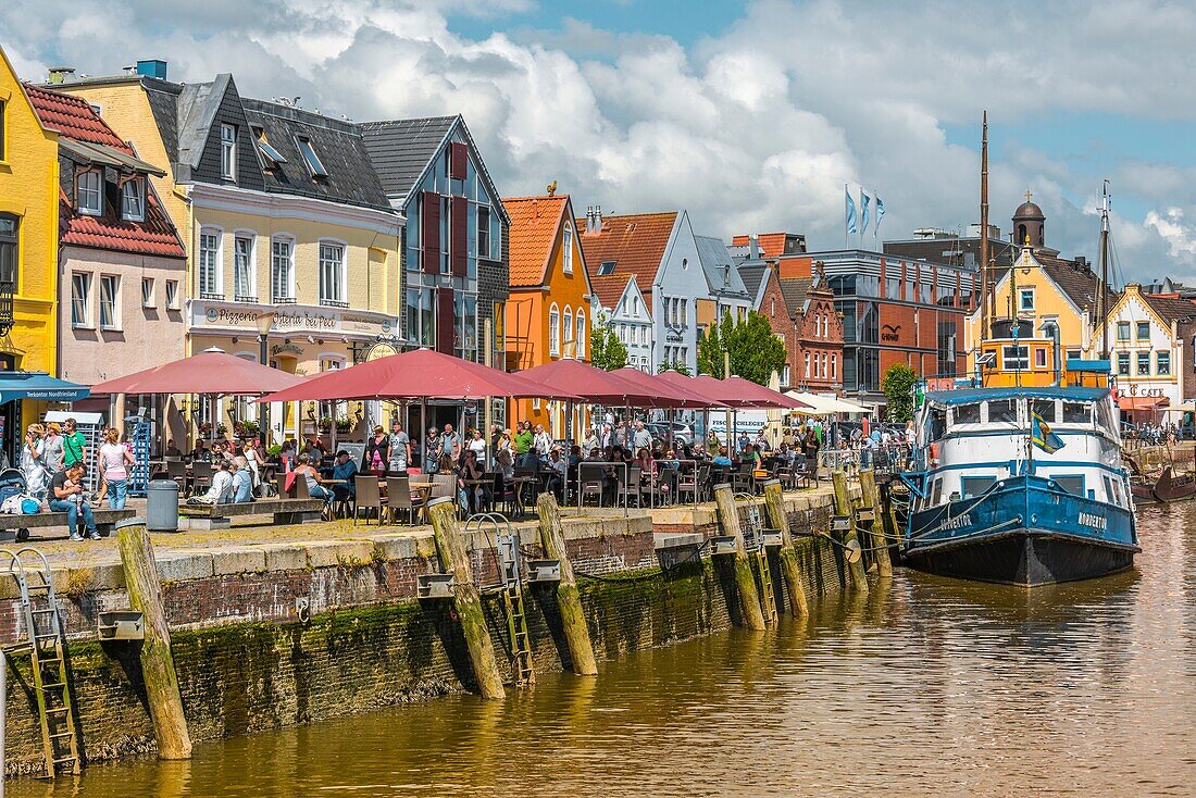 Pavement café and fish restaurants at the pier, inner harbour of the coastal town Husum at the North Sea, Germany.