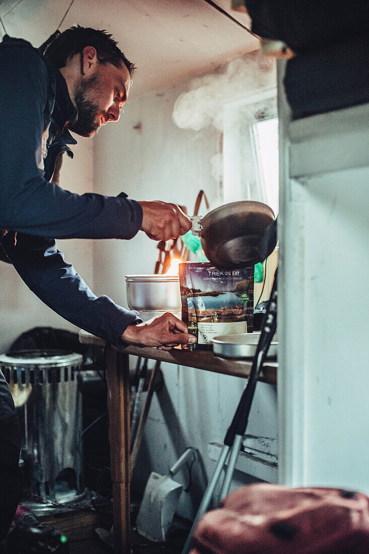 man cooking in a cabin, greenland, arctic.