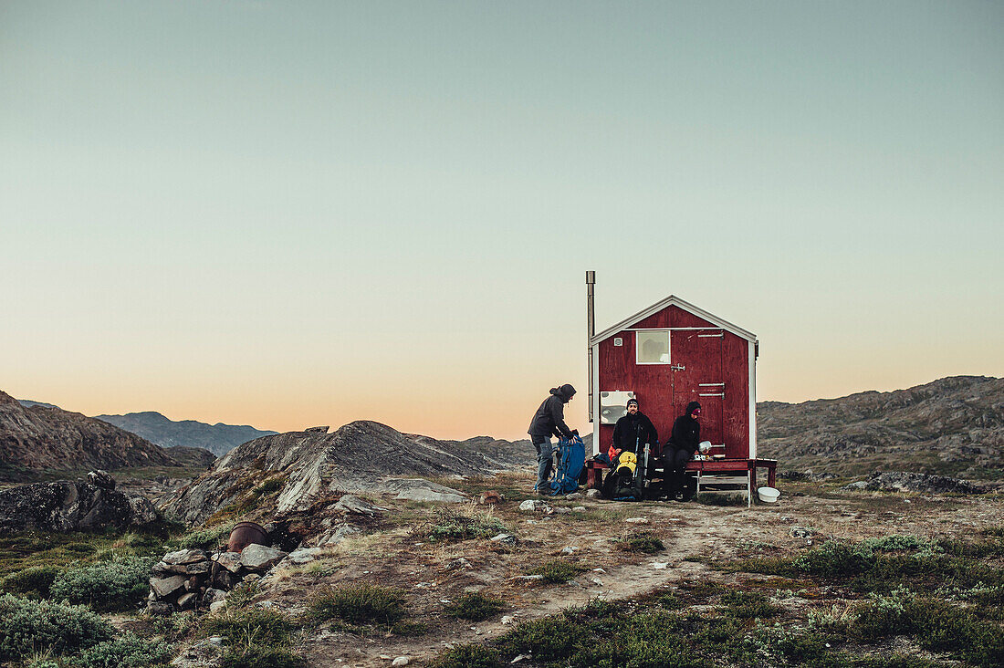 Wanderer vor einer roten Hütte in Grönland, Grönland, Arktis.