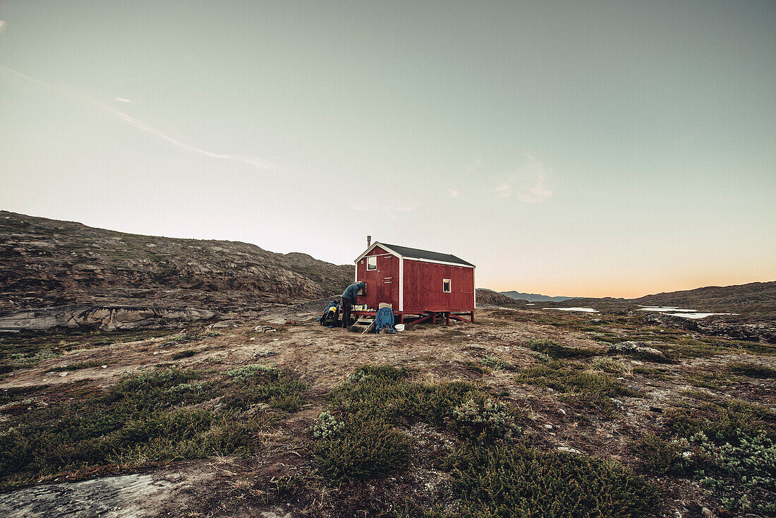 Mann kocht in einer Hütte, Grönland, Arktis.