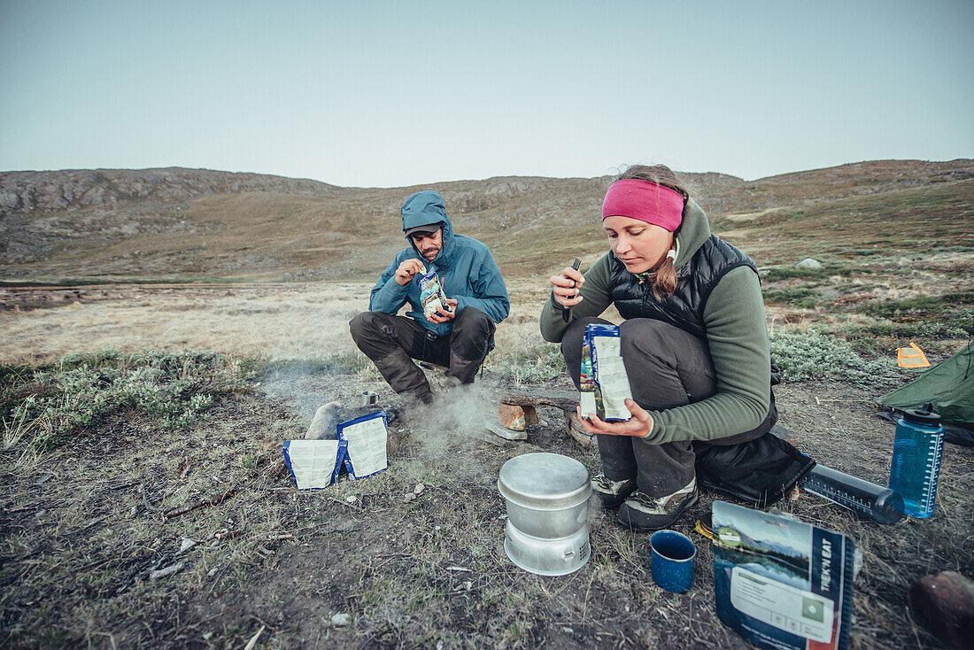 Hiker eating in front of a tent, greenland, arctic.