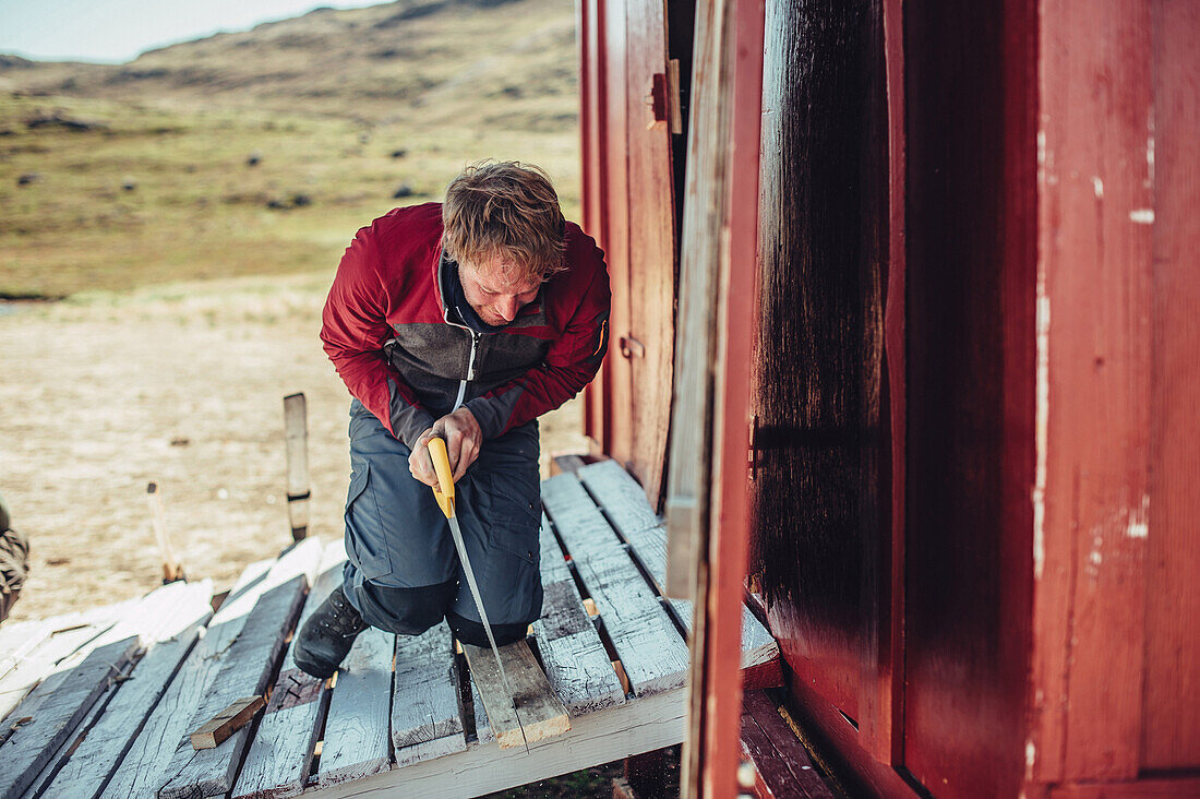 man cutting wood, greenland, arctic.