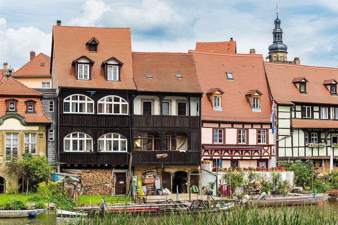 Old residential houses directly on the river Left Regnitzarm with the tower of the church St. Martin in the background, Bamberg, Bavaria, Germany