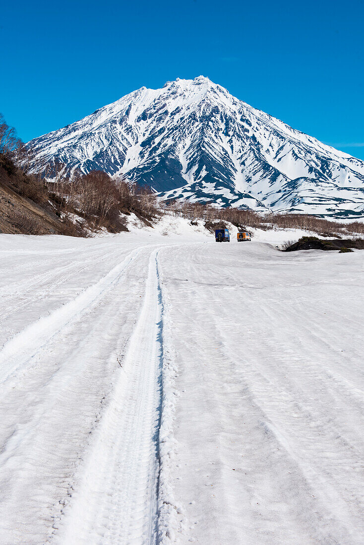 Blick auf den Koryaksky Vulkan mit großen Geländewagen davor, nahe Petropawlowsk-Kamchatsky, Kamtschatka, Russland, Asien