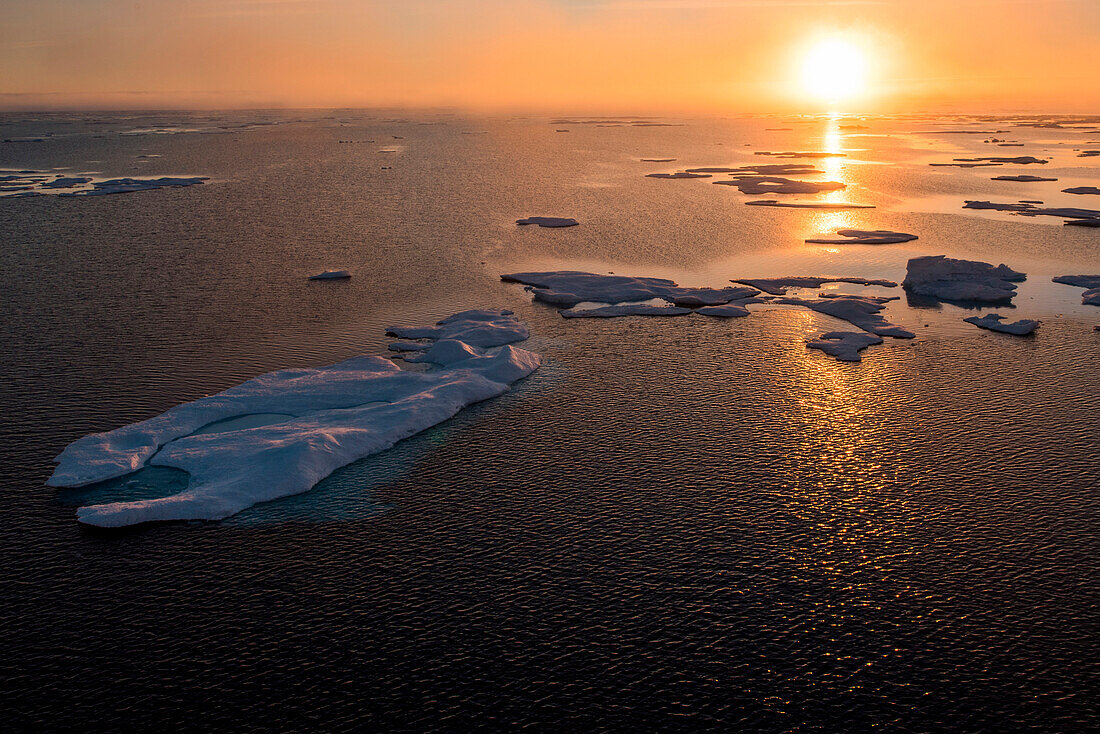 A golden sun rises over chunks of ice, near Prince of Wales Island, Nunavut, Canada, North America