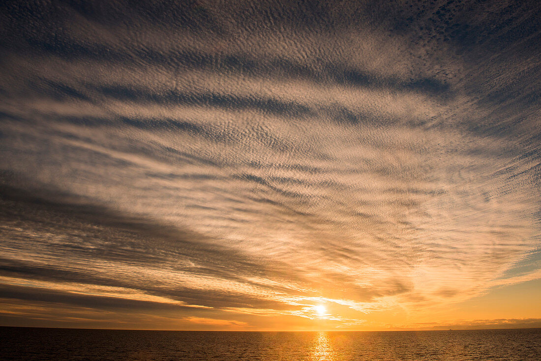 Ungewöhnliche Wolkenformationen heben einen goldenen Sonnenuntergang hervor, nahe Ilulissat (Jakobshavn), Diskobucht, Kitaa, Grönland