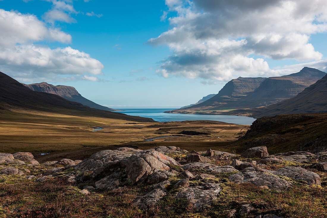 Rocky landscape opening toward the mountainous Seyðisfjörðdur fjord, near Seyðisfjörðdur, Eastern Iceland, Europe