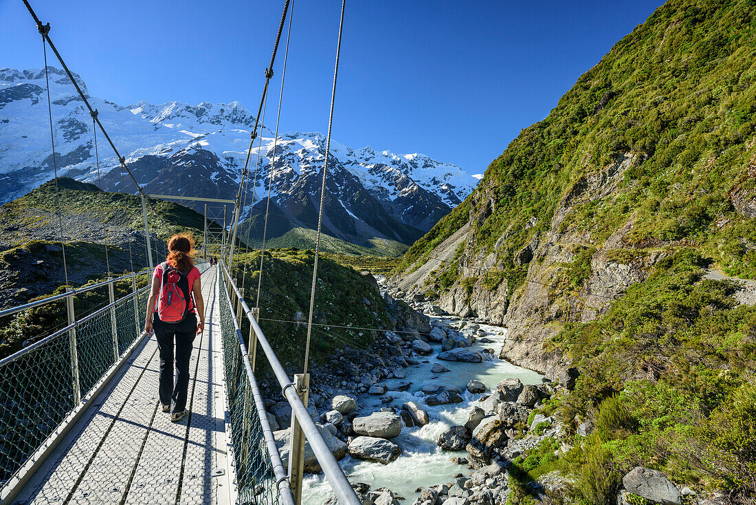 Frau überquert auf Hängebrücke Hooker River, Hooker Valley, Mount Cook, Mount Cook Nationalpark, UNESCO Welterbe Te Wahipounamu, Canterbury, Südinsel, Neuseeland