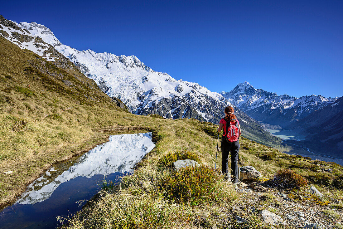 Frau wandert an Bergsee mit Spiegelung, Mount Sefton, Mount Cook und Hooker Valley im Hintergrund, Hooker Valley, Mount Cook Nationalpark, UNESCO Welterbe Te Wahipounamu, Canterbury, Südinsel, Neuseeland