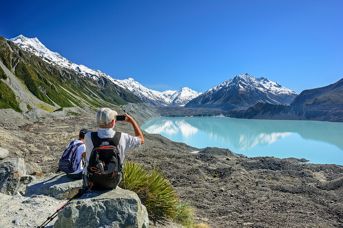 Man taking a photo of glacier lake and Tasman glacier with Mount Cook in background, Tasman Valley, Mount Cook National Park, UNESCO Welterbe Te Wahipounamu, Lake Pukaki, Canterbury, South island, New Zealand