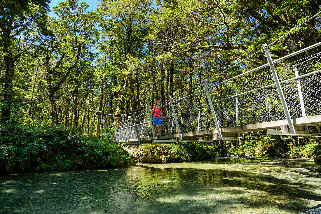 Frau wandert auf Hängebrücke über Routeburn Fluss, Routeburn Track, Great Walks, Fiordlands Nationalpark, UNESCO Welterbe Te Wahipounamu, Queenstown-Lake District, Otago, Südinsel, Neuseeland