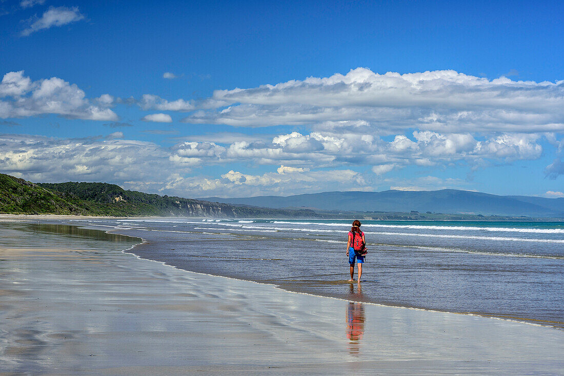 Woman hiking on beach, Tasman Sea, Hump Ridge, Hump Ridge Track, Fiordlands National Park, UNESCO world heritage Te Wahipounamu, Southland, South island, New Zealand
