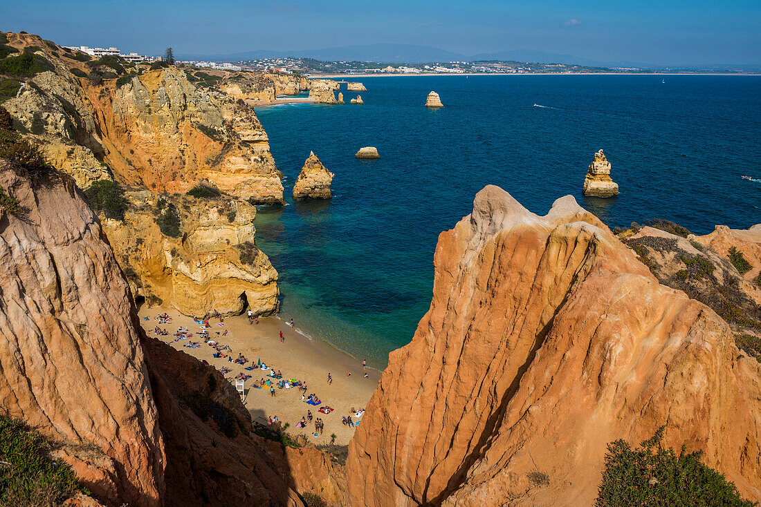 Swimmers on the beach between steep cliffs, Praia do Camilo, Lagos, Algarve, Portugal