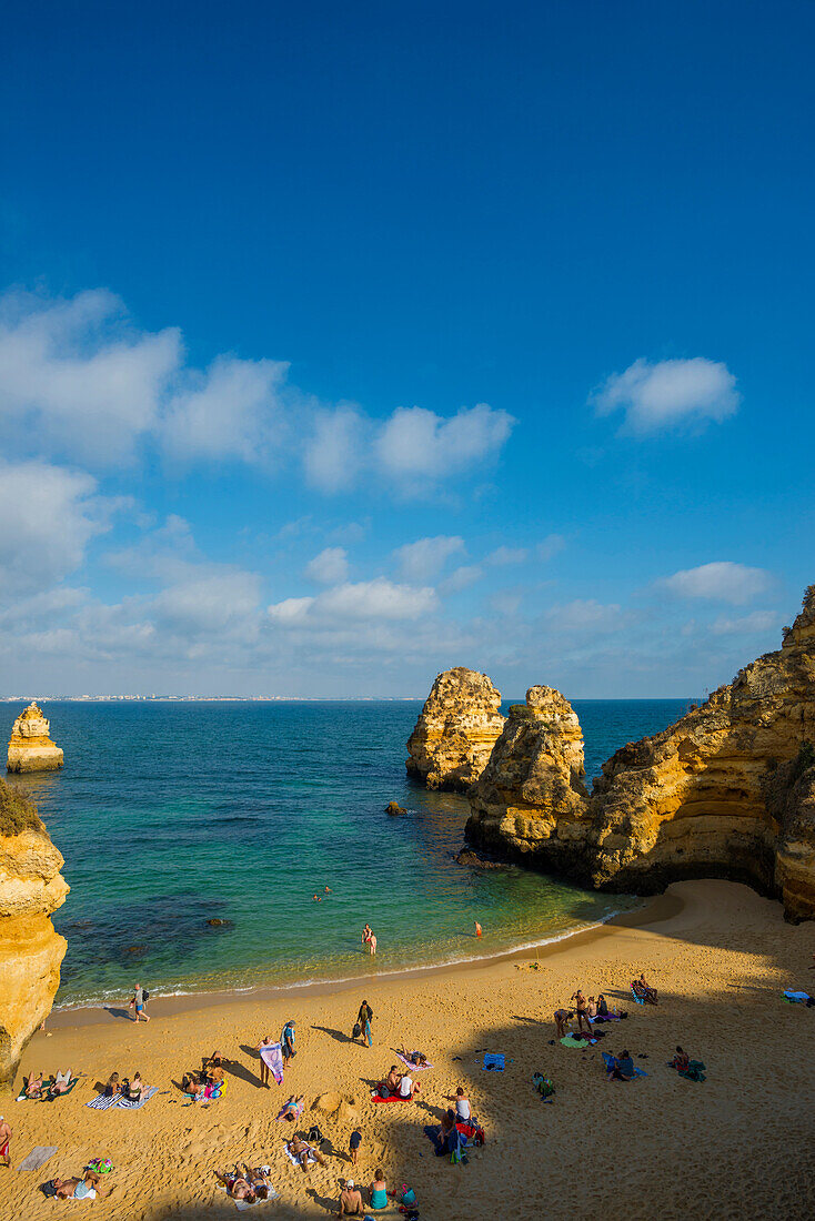 Swimmers on the beach between steep cliffs, Praia do Camilo, Lagos, Algarve, Portugal