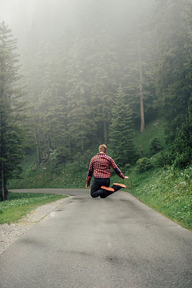 Mann springt auf einer Straße im Brandnertal, Vorarlberg, Österreich, Europa.