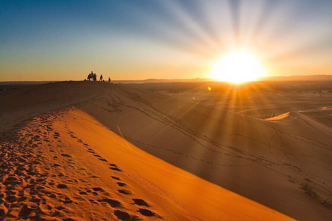 People on a dunes watching the sunset, dunes near Merzouga south of  Rissani in the Erg Chebbi, Morocco