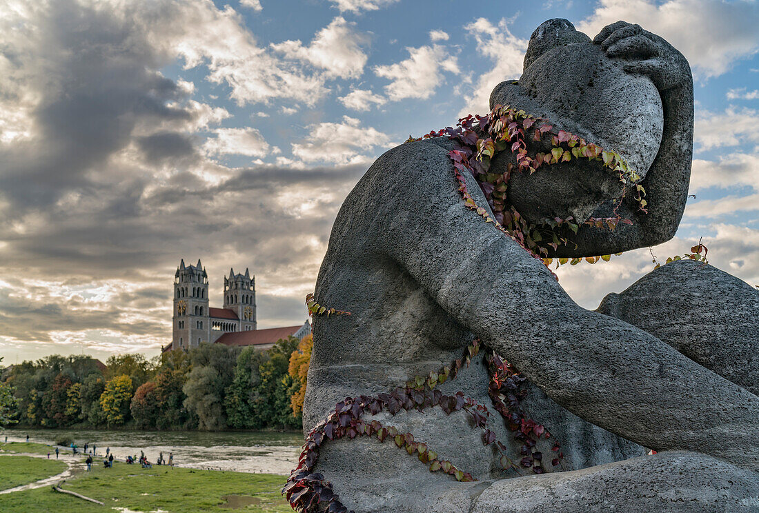 Statue on the Reichenbach bridge with autumnal ivy, in the background the Isarbank with passerby's and church of St. Maximilian, Munich, Upper Bavaria, Germany