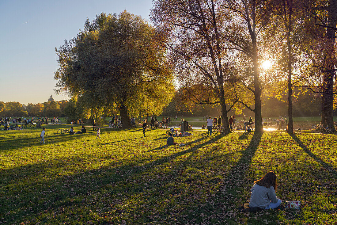 Autumnal Scene at the Eisbach in Englischer Garten, People on the green, Passer by, Munich, Upper Bavaria, Germany