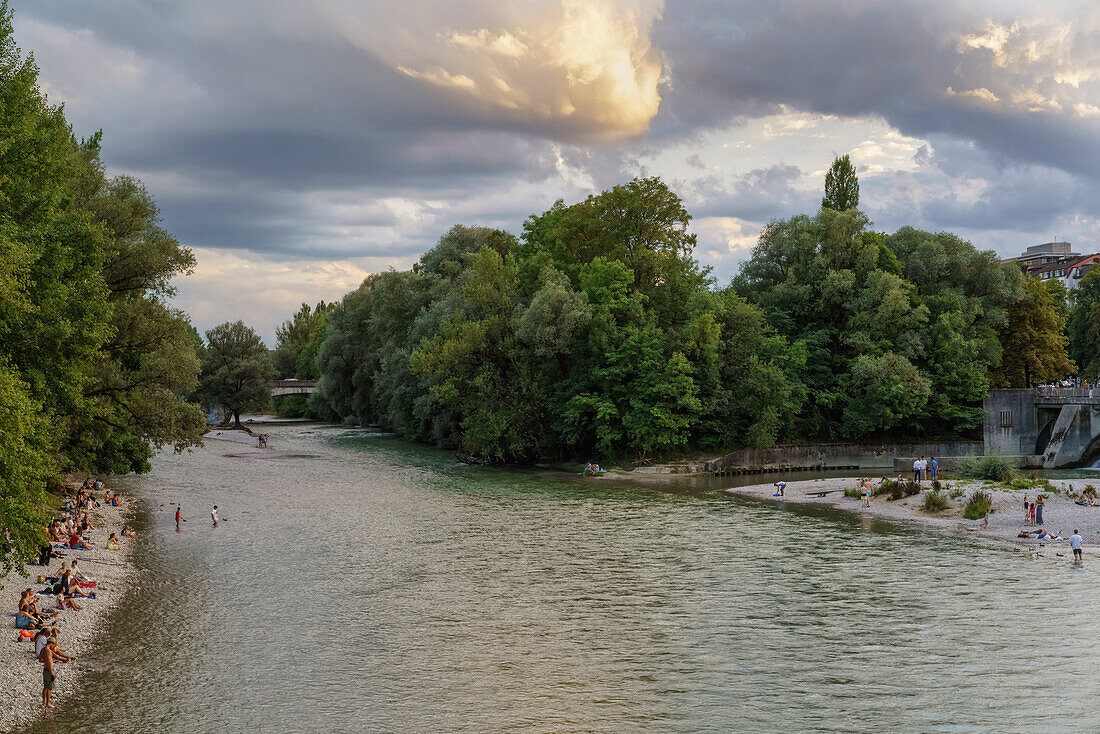 View on the gravel banks at the Muffathalle from Kabelsteg to direction Ludwigsbruecke, visitors enjoying the evening along the river Isar, Munich, Upper Bavaria, Germany