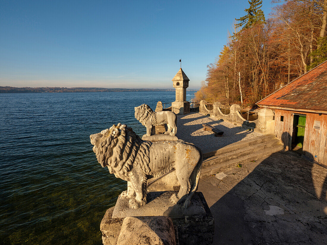 The two lions and the tower of the bathing area of Schloss Seeburg at lake Starnberger see in the setting sun, Muensing, Upper Bavaria, Germany