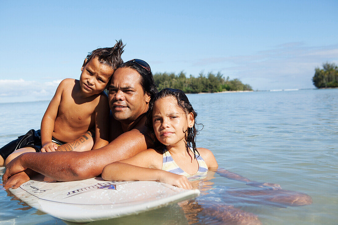 FRENCH POLYNESIA, Moorea. Portrait of Tattoo Artist James Samuela with his kids before surfing.